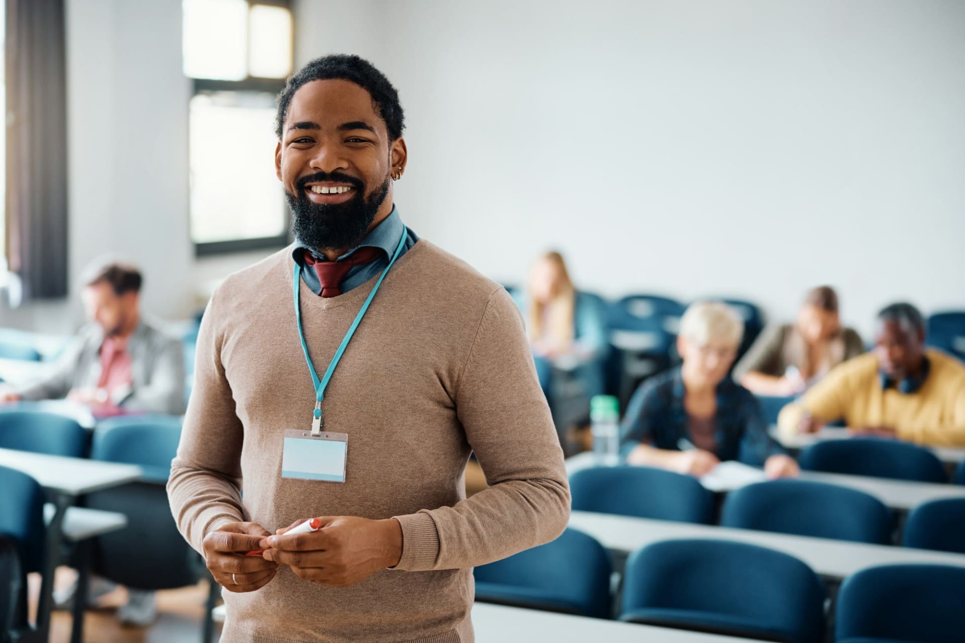 Happy black adult education teacher in lecture hall looking at camera.